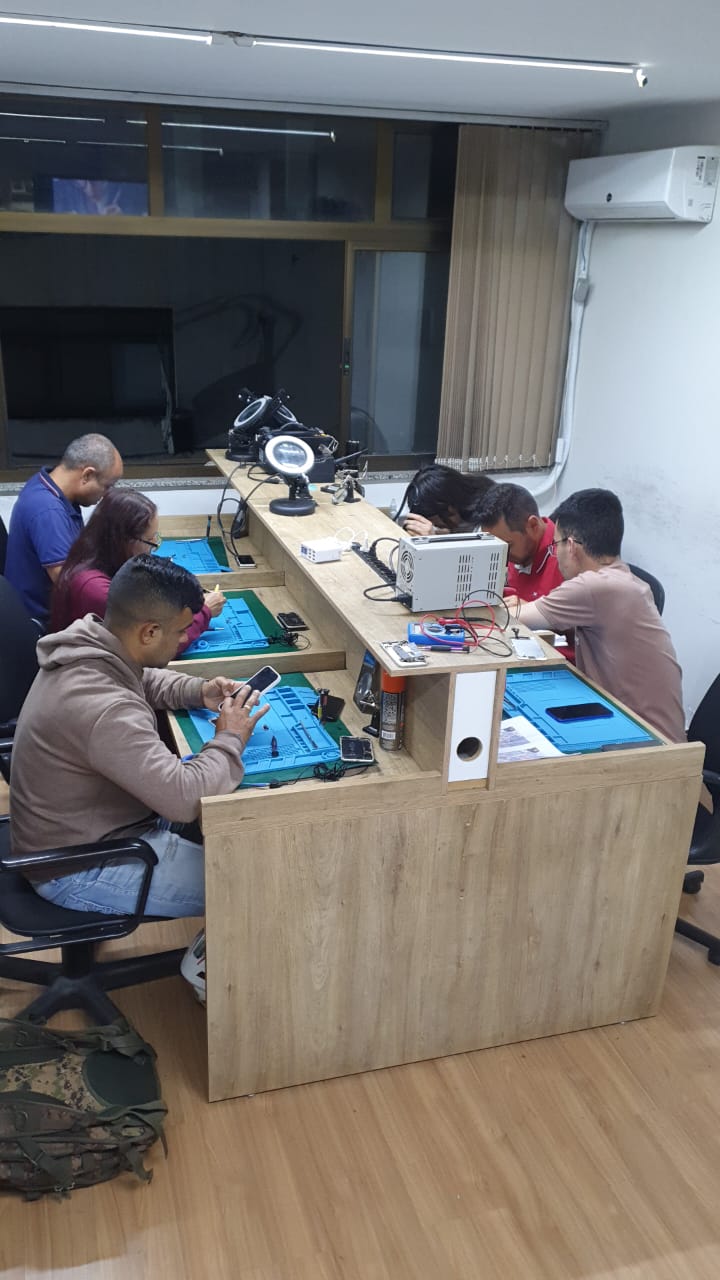 Turma em aula presencial de reparo de celulares